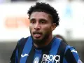 Primer plano de Éderson dos Santos, jugador de fútbol con pelo rizado y barba, vistiendo una camiseta a rayas azules y negras.