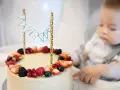 Słodki tort z owocami na przyjęcie dla dzieci. Maluch z zaciekawieniem patrzy na pyszny deser.