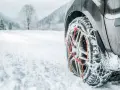 Ruota di un'auto con catene da neve su una strada innevata. Per affrontare la neve, quante catene da neve servono? Di solito due, una per ogni ruota motrice.