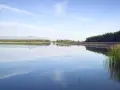Spokojny zalew Dziećkowice z odbijającymi się w tafli wody chmurami i zielonym lasem w tle.
