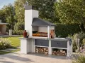Una moderna zona barbecue in giardino, con camino, piano di lavoro, lavello e legna da ardere.