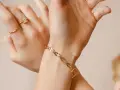 Mani adornate con anelli e un bracciale in metallo che sembra oro, un tocco di eleganza discreta.