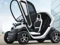 Biały, dwumiejscowy kei car z otwartymi drzwiami, zaparkowany przed nowoczesnym budynkiem.