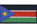 Naszywka z flagą Sudanu Południowego. Czarny pas na górze, pod nim biały, czerwony i zielony pas. Z lewej strony niebieski trójkąt z żółtą gwiazdą.