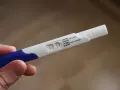Dłoń trzyma test ciążowy z dwoma kreskami, co oznacza, że test ciążowy negatywny.