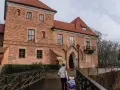 Rodzina idzie drewnianym mostkiem do ceglanego zamku w Oporowie.