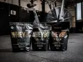 Tre påsar med Wellaware Whey80 proteinpulver står uppradade på ett gymgolv. Perfekt för återhämtning efter träning, oavsett om du föredrar vassle eller kasein.