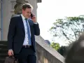 Anwalt am Telefon, der überlegt, wie kann ich mich schnell scheiden lassen. Er trägt einen dunklen Anzug und hält eine Aktentasche.