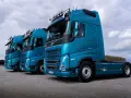 Rząd lśniących, turkusowych ciężarówek Volvo FH gotowych do transportu żywności.