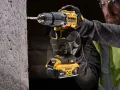 Mężczyzna w rękawicach wierci w betonie najmocniejszą wkrętarką DeWalt 18V XR.