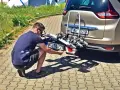 Mężczyzna montuje tablicę rejestracyjną na bagażniku rowerowym, by uniknąć mandatu za brak tablicy rejestracyjnej na bagażniku rowerowym.
