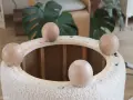 Quatre pieds ronds en bois sont posés sur le bord d'un pouf rond en tissu bouclette, prêt à recouvrir.