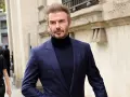 David Beckham luce un elegante traje azul con jersey de cuello alto, caminando con confianza.