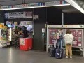 Na dworcu w Rzymie Ciampino ludzie kupują bilety i artykuły w sklepie.