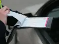 Funkcjonariusz wypisuje mandat karny po kolizji drogowej. Dokument zawiera numer sprawy i szczegóły wykroczenia.
