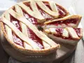 Una deliziosa crostata ricotta e marmellata, con una fetta tagliata per mostrare il ripieno cremoso e la crosta dorata.