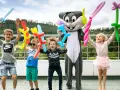 Radosne dzieci z balonami w kształcie zwierzątek i mieczy świętują koniec roku szkolnego z postacią królika.