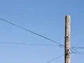 Słup energetyczny z przewodami, symbolizujący zgodę na światłowód nad działką.