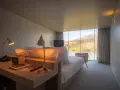 Un angolo studio in camera da letto con vista sul lago. Due lampade illuminano la scrivania con telefono e altoparlante.