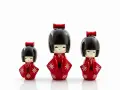 Trzy urocze lalki kokeshi w czerwonych kimonach z białymi wzorami. Idealny pomysł, co przywieźć z Japonii jako pamiątkę.