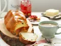 Pyszne, złociste ciasto drożdżowe, pokrojone w plastry, z dżemem, masłem i kawą. Idealne na śniadanie.