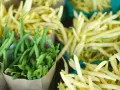 Zielona i żółta fasolka szparagowa w papierowych torbach i zielonych pojemnikach. Idealny czas, kiedy jest sezon na fasolkę szparagową.