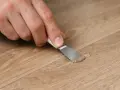 Mano che ripara un piccolo buco nel muro con una spatola e stucco.