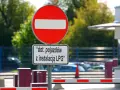 Znak B2 "zakaz wjazdu" z tabliczką informującą, że dotyczy pojazdów z instalacją LPG. Za znakiem widać szlaban i samochody.