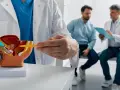 Lekarz omawia z pacjentem model układu moczowo-płciowego, wskazując na obszar prostaty. Rozmowa dotyczy potencjalnych objawów raka prostaty.
