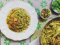 Makaron z pesto ze słoika, posypany pistacjami i kawałkami suszonych pomidorów, prezentuje się apetycznie na talerzu.