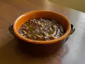 Una ciotola di terracotta con un saporito piatto di pasta e lenticchie, condito con olio d'oliva.