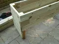 Påbörjat projekt att bygga blomlåda av tryckimpregnerat virke. Några krukor med jord står redo.