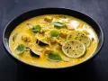 Aksamitne curry z kurczakiem, makaronem i plasterkami cukinii, ozdobione świeżą bazylią i limonką.