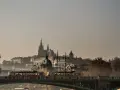 Most w Czechach, po którym przejeżdża tramwaj, z widokiem na zabytkowe budowle w oddali.