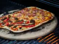 En läcker pizza på grillen med skinka, ananas, kött och paprika. En perfekt sommarmåltid!
