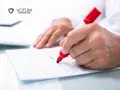 Ręka zaznacza czerwonym markerem potencjalne błędy w umowach kredytowych. VOTUM Consumer Care pomaga w analizie dokumentów.
