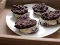 Cztery domowe ciastka z kremem, przypominające Oreo, na białym talerzu. Pyszna przekąska, choć warto sprawdzić oreo kcal przed zjedzeniem.
