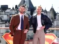 Due uomini posano con stile: uno in completo marrone, dimostrando come abbinare il marrone uomo con eleganza, l'altro con giacca di pelle e pantaloni chiari.