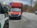 Czerwony bus Renault na drodze, obok pojazd inspekcji. Może to być związane z wnioskiem o wypis z licencji transportowej.