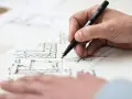 Dłoń rysuje plany architektoniczne, uwzględniając objętość właściwą.