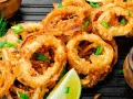 Aros de calamar rebozados y fritos, servidos con limón y salsa de tomate. Ideales para recetas con calamares.