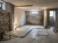 Cantina in ristrutturazione, con pareti in pietra grezza e cemento. Si nota la preparazione per l'isolamento del pavimento umidità.