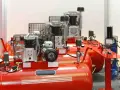 Kilka czerwonych sprężarek tłokowych z metalowymi osłonami i manometrami. Kierunek obrotów sprężarki tłokowej jest kluczowy dla jej prawidłowego działania.