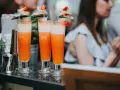 Orzeźwiający drink dla kobiet, ozdobiony owocami i listkami, gotowy do podania na letnim przyjęciu.