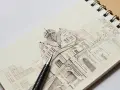 Szkice ołówkiem galeria: rysunek architektoniczny zabytkowych budynków z detalami i cieniowaniem, obok leży ołówek.