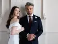 Elegancki pan młody ślub cywilny w granatowym garniturze i jego uśmiechnięta narzeczona w białej sukni.