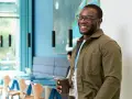 Ein Mann mit Brille lächelt und hält eine Tasse. Er könnte sein **Praktikum im Ausland** genießen und neue Eindrücke sammeln.