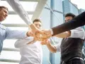 Un gruppo di uomini d'affari unisce i pugni, mostrando le loro caratteristiche personali di unità e determinazione.