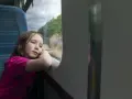 Dziewczynka wpatrzona w okno pociągu, zastanawia się, od ilu lat można jeździć samemu pociągiem.