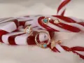 Złote kolczyki, w tym ozdobny pierścień na anti helix, błyszczą na tle cukierków.